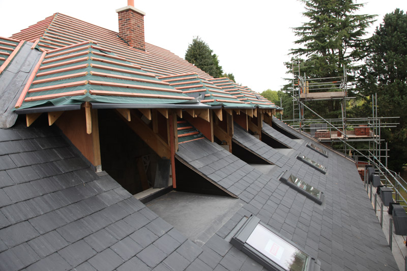 A dormer roof being built, with scaffold round the house